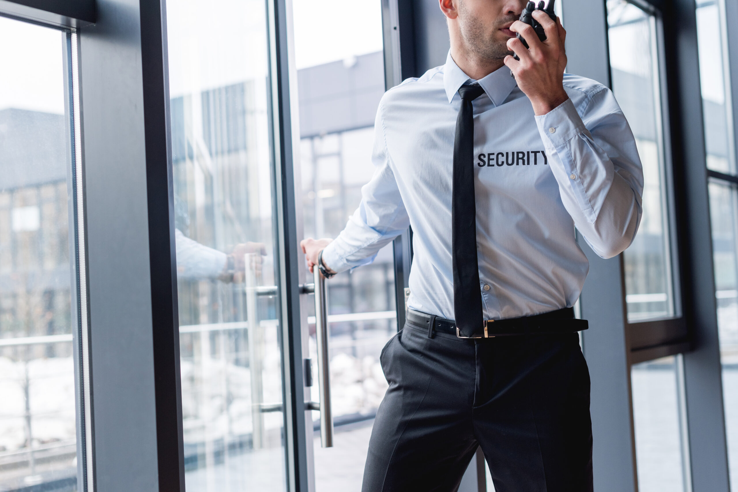cropped view of handsome guard in suit talking on walkie-talkie